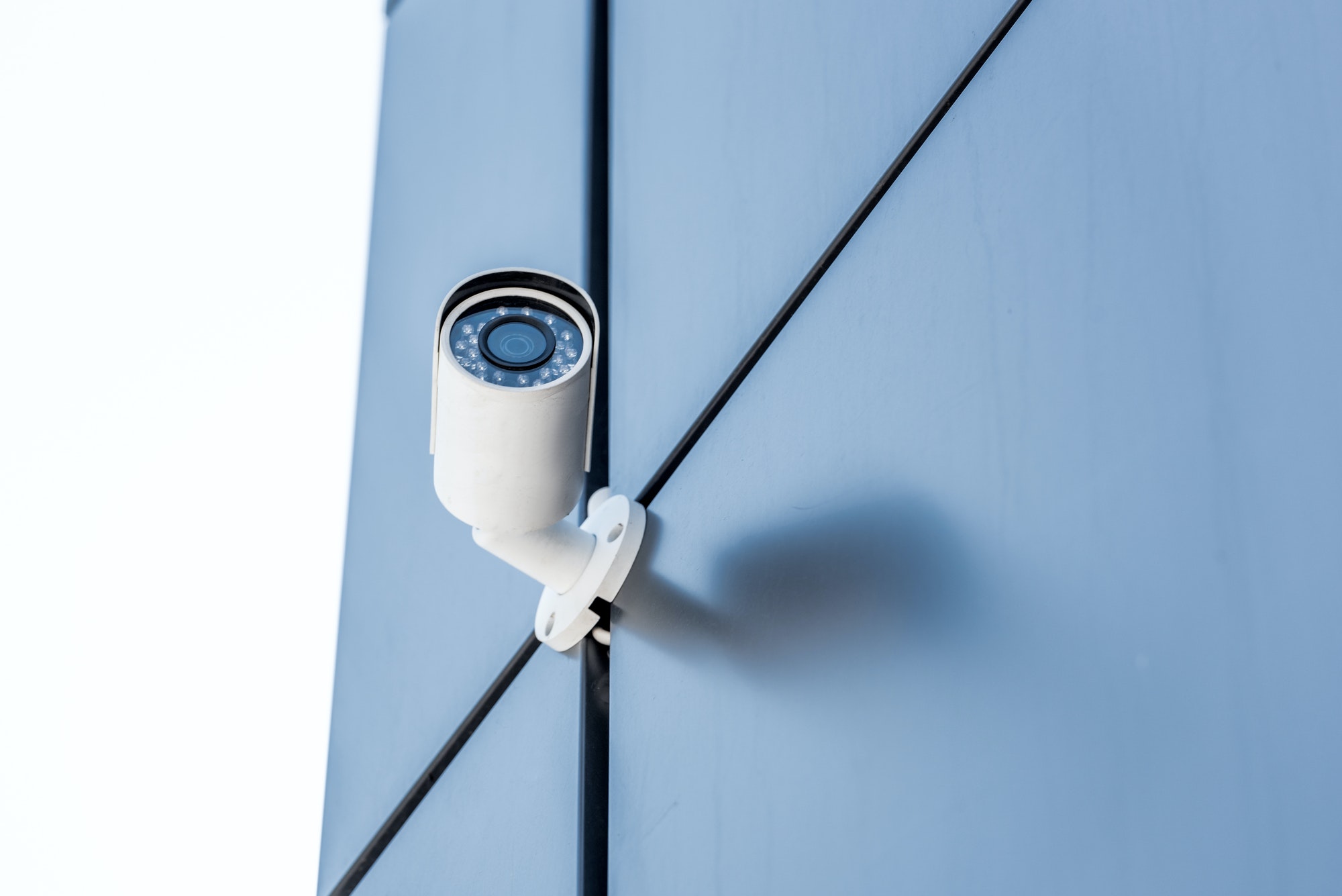 one security camera on blue wall of office building, security system concept